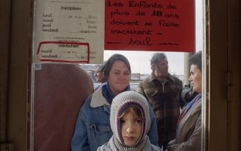 Un jeune garçon attend derrière la porte l'ouverture des &quot;Restos du Cœur&quot; de Lisieux, le 21 décembre 1989, jour du début de la campagne officielle dans toute la France © Mychèle Daniau / AFP