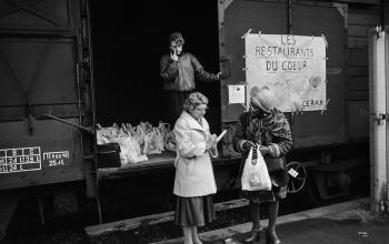 Des bénévoles des Restos du Cœur distribuent des sacs de nourriture depuis un wagon de la SNCF à Cannes, le 29 décembre 1985 © Christophe Simon / AFP