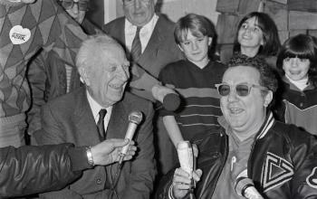 Coluche et le maire de Marseille Gaston Deferre présentent à la presse le 18 janvier 1986 une campagne en faveur des Restos du Cœur et plaident pour l'élaboration d'une loi donnant plus de pouvoir aux associations caritatives. À l'occasion de cette visite, une opération de récupération de denrées alimentaires sera organisée sur les parkings de 14 supermarchés de la région © Pierre Ciot / AFP